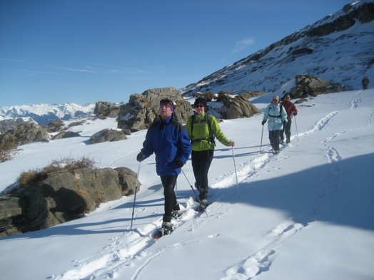 Eine Gruppe Schneeschuhlaeufer zwischen grossen Felsbrocken.
