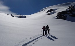 Zwei Skitourenfahren ziehen ihre Aufstiegsspur im unberührtem Schnee.